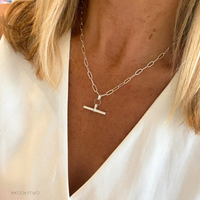 Silver necklace with t-bar pendant pendant worn by a person in white waistcoat.