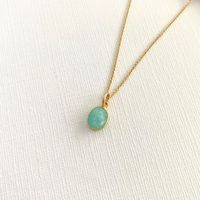 Gold necklace with a turquoise pendant on a white fabric background