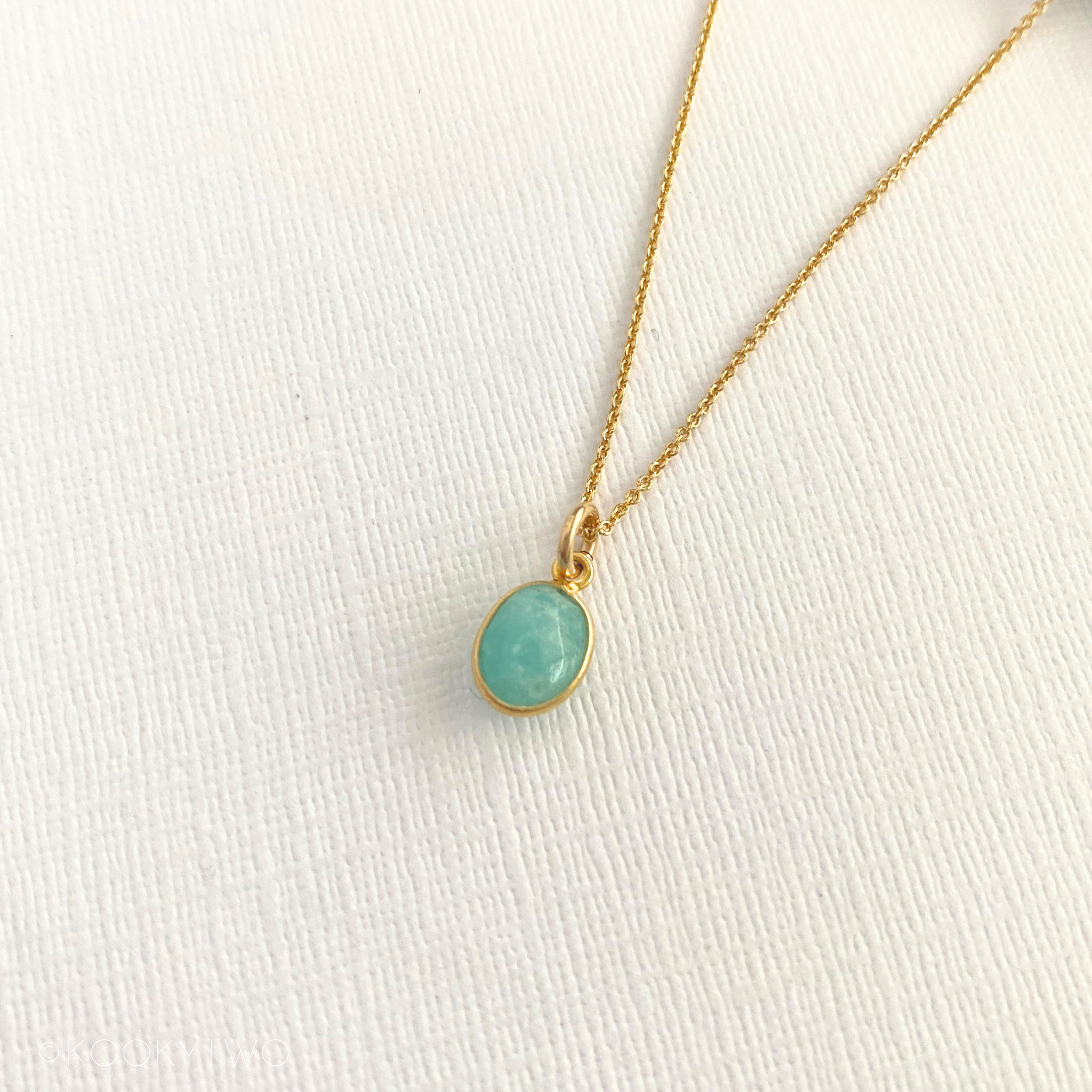 Gold necklace with a turquoise pendant on a white fabric background