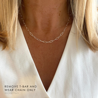 Plain silver chain necklace worn by a person with a plain background