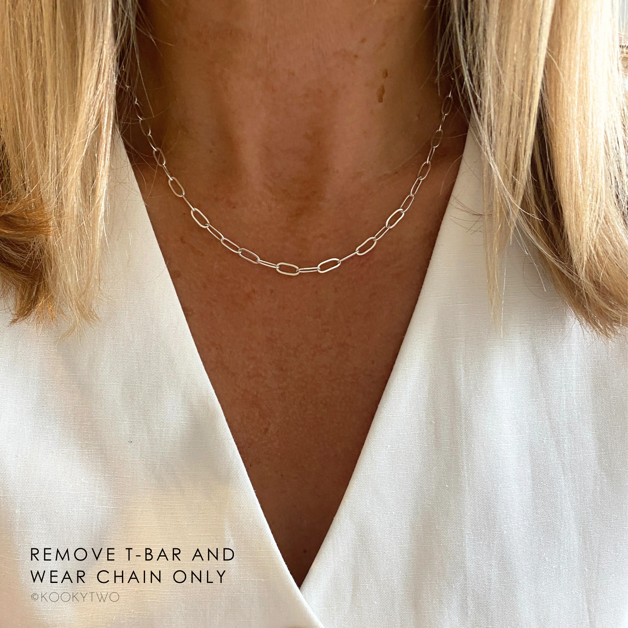 Plain silver chain necklace worn by a person with a plain background