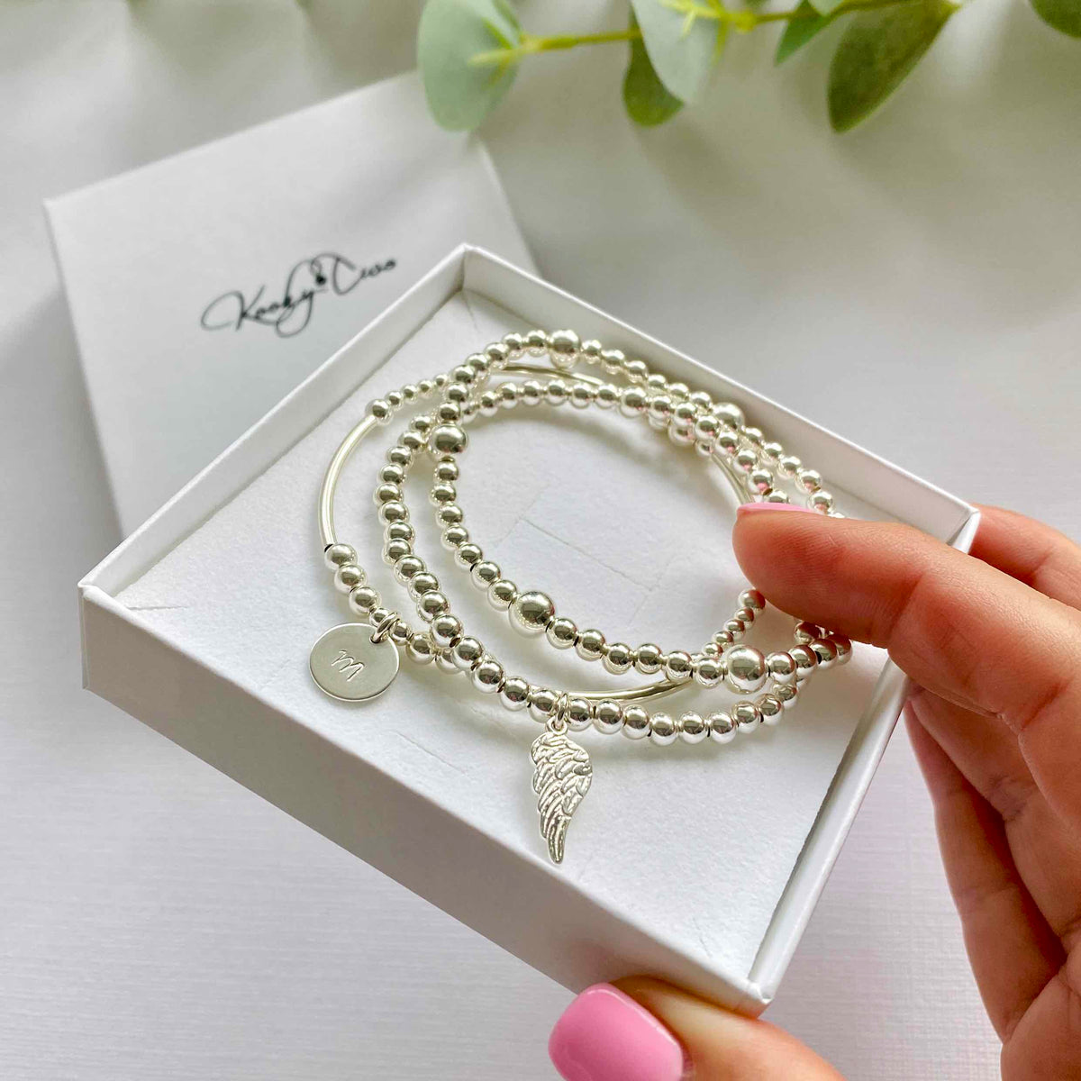 Set of three bracelets with personalised disc bracelet, plain silver bead bracelet and angel wing bracelet. Hand beaded silver bead bracelets. KookyTwo Personalised Bracelet Jewellery.