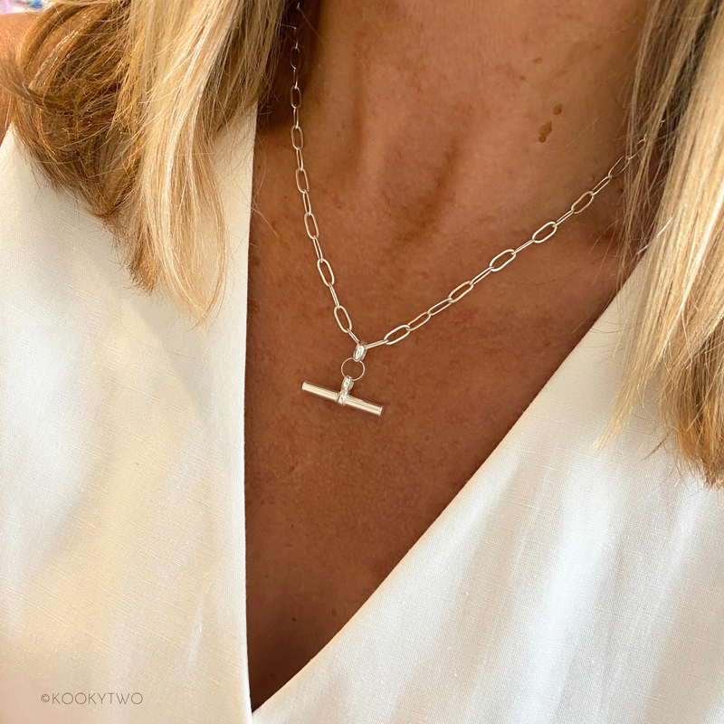 Silver necklace with t-bar pendant pendant worn by a person in white waistcoat.