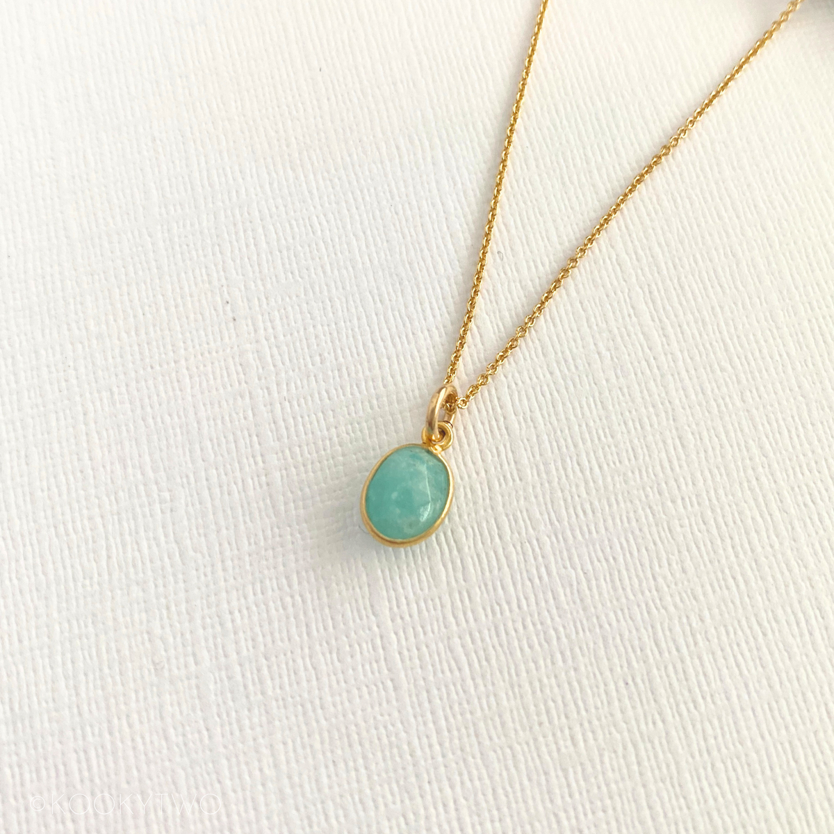 Gold necklace with a turquoise pendant on a white fabric background