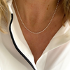 Silver belcher chain necklace worn by a person with a white blouse with black edging.