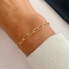Gold chain bracelet on a wrist with a white sleeve