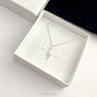 Sterling silver necklace with a crystal lightning bolt pendant in an open white jewellery box on a light surface.