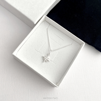 Sterling silver necklace with a star pendant in a white jewellery box on a white surface.