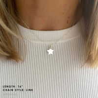 Star-shaped necklace on a person wearing a light-coloured top.