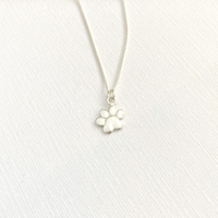 Silver necklace with a paw-shaped pendant on a white fabric background