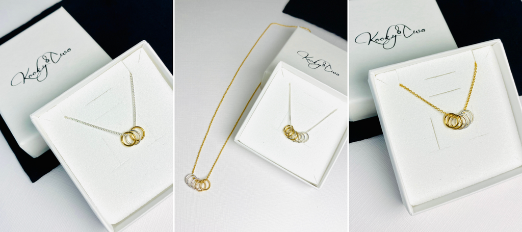 Silver and gold necklaces with dainty rings to represent family members.