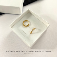 Huggie Gold Earring hoops in a white box.