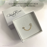 Box with gold and crystal ear jacket with chain between two crystal stones. Branding on box is KookyTwo.