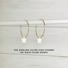 Gold hoop earrings with star charms on a light wooden background