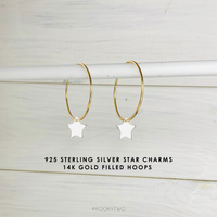 Gold hoop earrings with star charms on a light wooden background