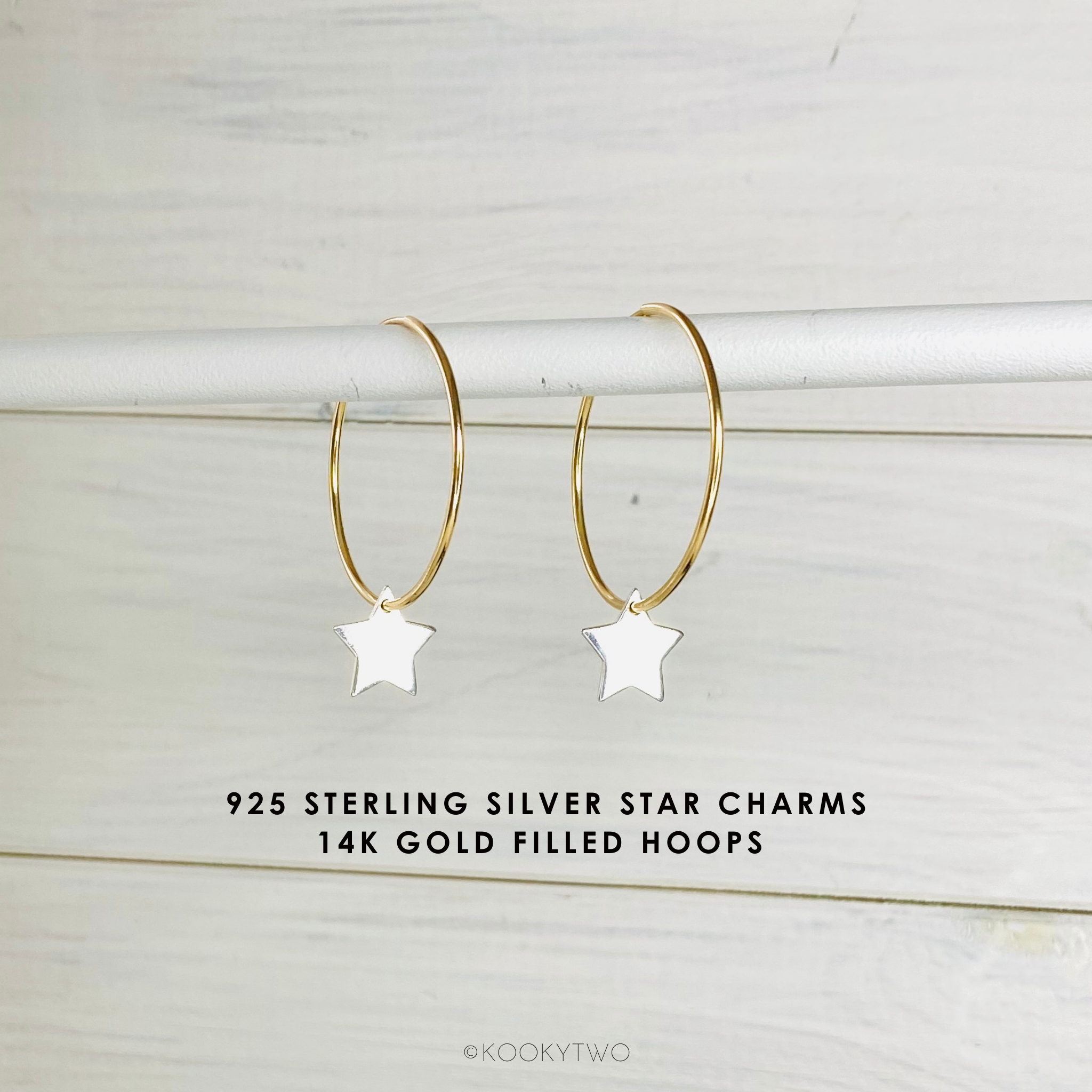Gold hoop earrings with star charms on a light wooden background