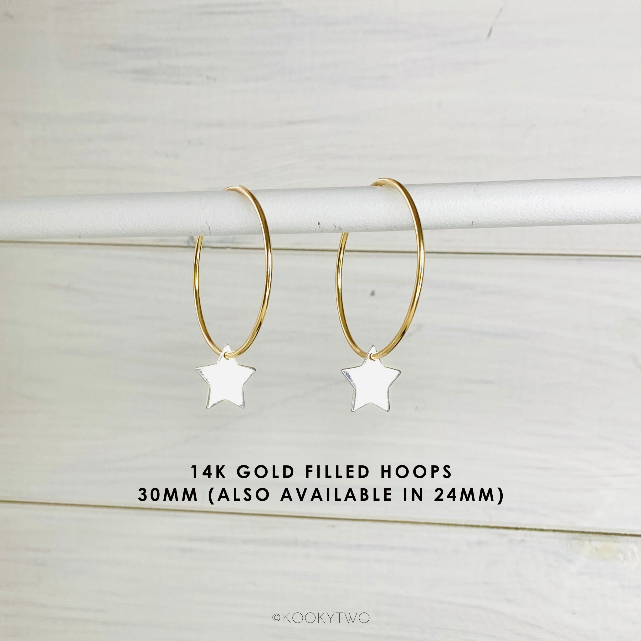 Gold hoop earrings with star charms on a light wooden background