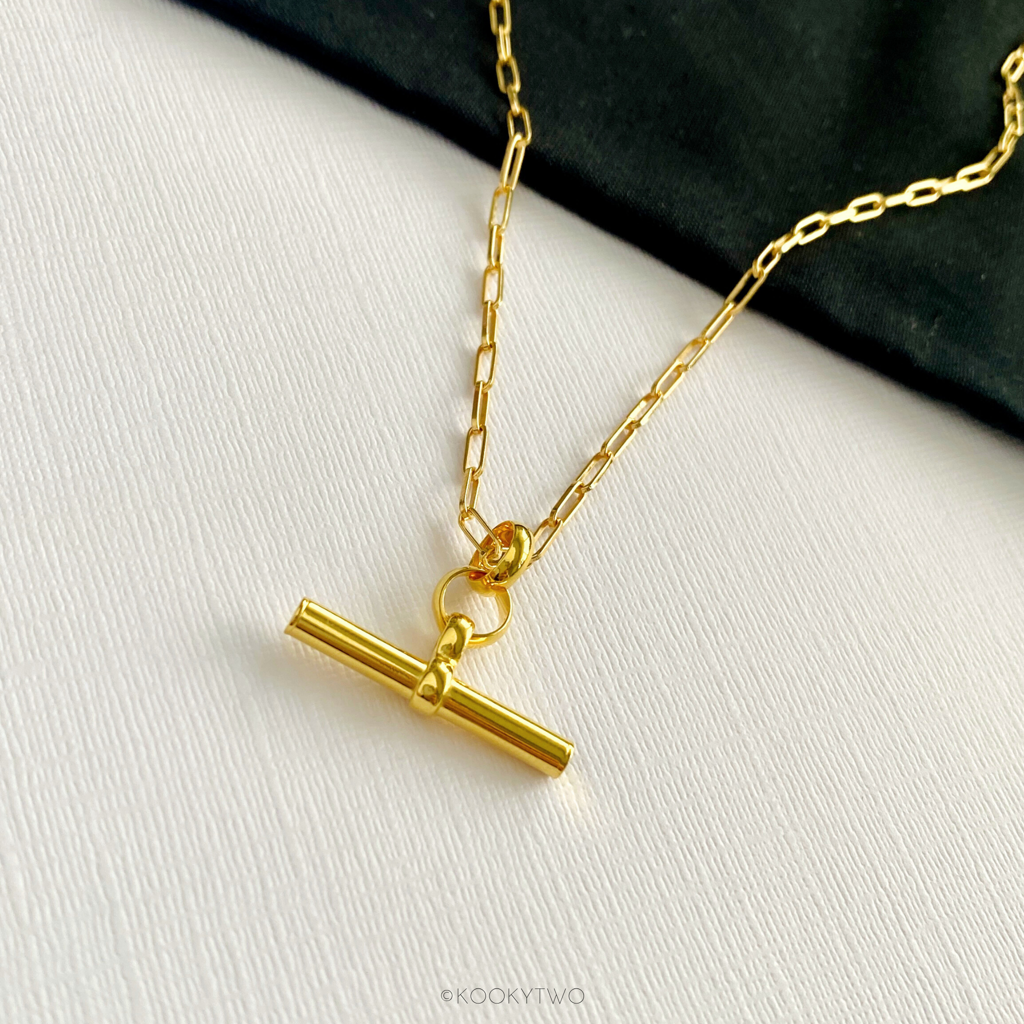 Close-up of chunky hanging T-bar charm necklace, showing its sleek and polished design, handmade with gold vermeil paperclip chain. KookyTwo.