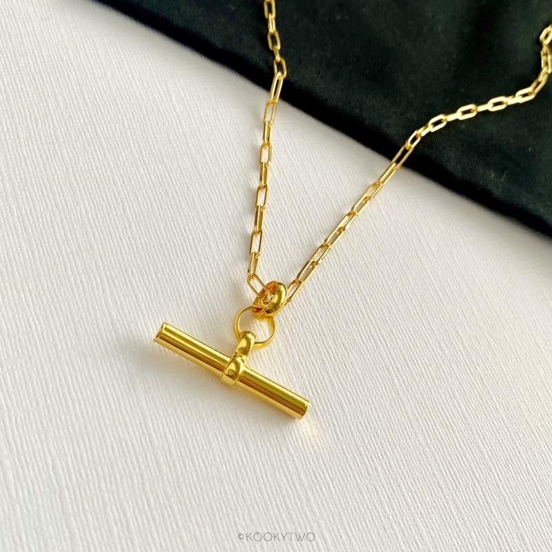 Close-up of chunky hanging T-bar charm necklace, showing its sleek and polished design, handmade with gold vermeil paperclip chain. KookyTwo.