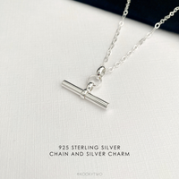 925 Sterling silver necklace with a simple plain t bar charm on a silver chain, displayed on a textured white surface with text overlay '925 STERLING SILVER CHAIN AND SILVER CHARM'.