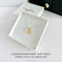 Mixed metal silver and gold necklace with capital letter pendants in a white gift box on a white background.