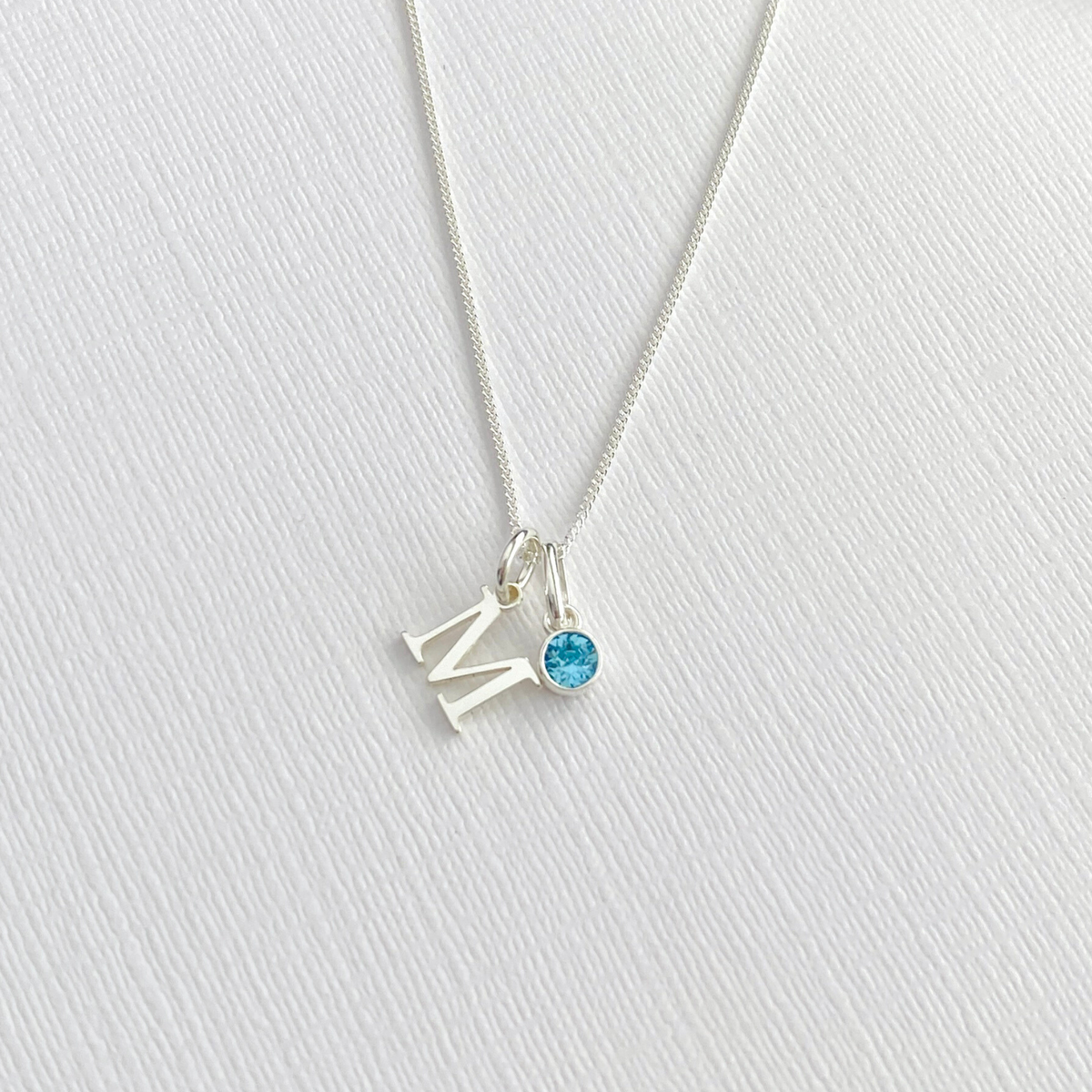 A delicate sterling silver initial necklace, with a blue crystal. Custom initial necklace in a minimalist, elegant style, perfect for everyday wear. KookyTwo.