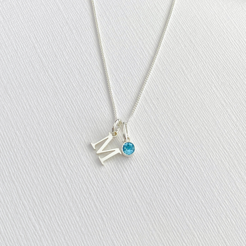 A delicate sterling silver initial necklace, with a blue crystal. Custom initial necklace in a minimalist, elegant style, perfect for everyday wear. KookyTwo.