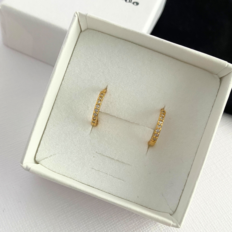 Gold hoop earrings in a white jewellery box.