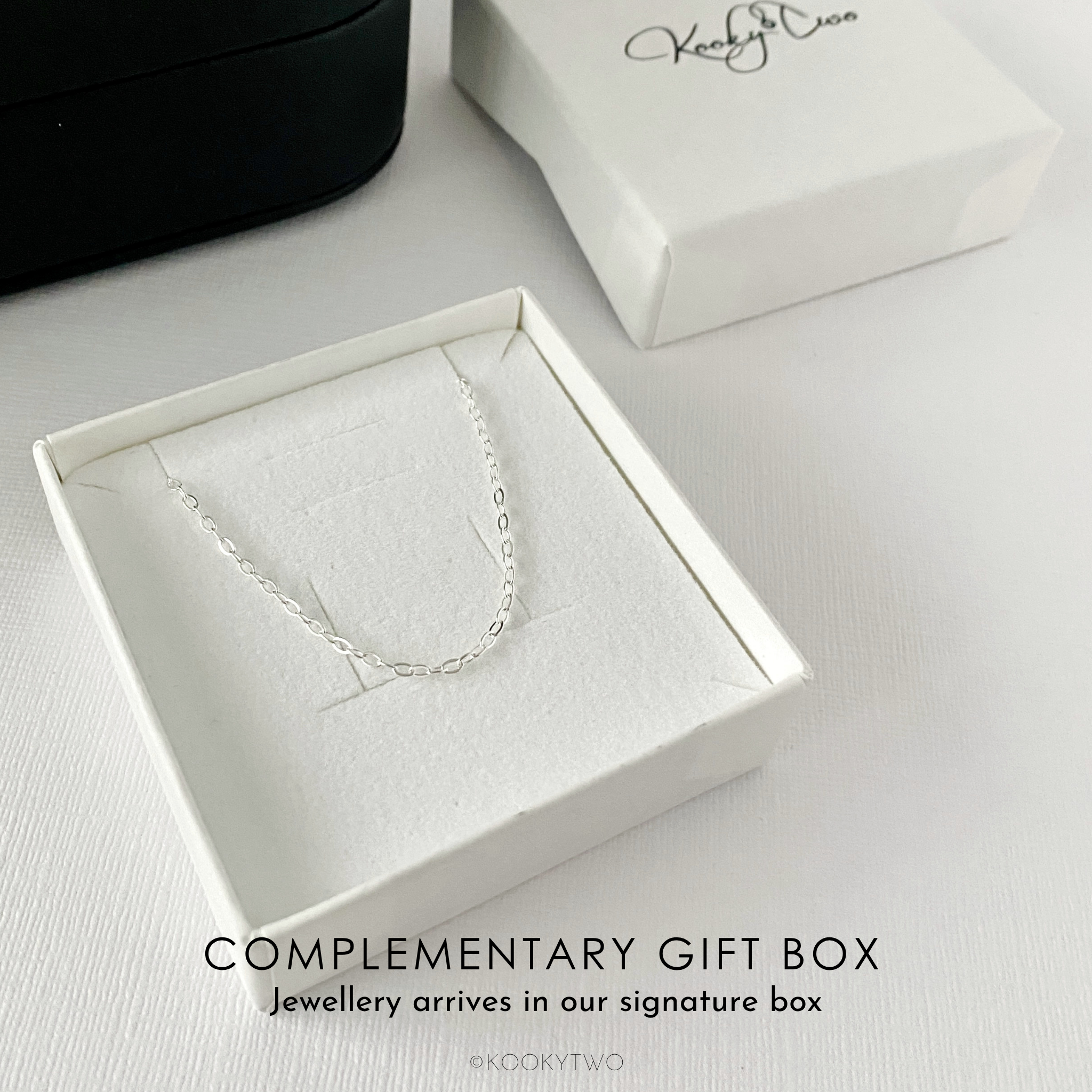 A sterling silver chain necklace displayed inside an open white gift box with a textured insert, alongside a closed white box with a black script logo KookyTwo. Text at the bottom reads 'COMPLEMENTARY GIFT BOX' and 'Jewellery arrives in our signature box'.