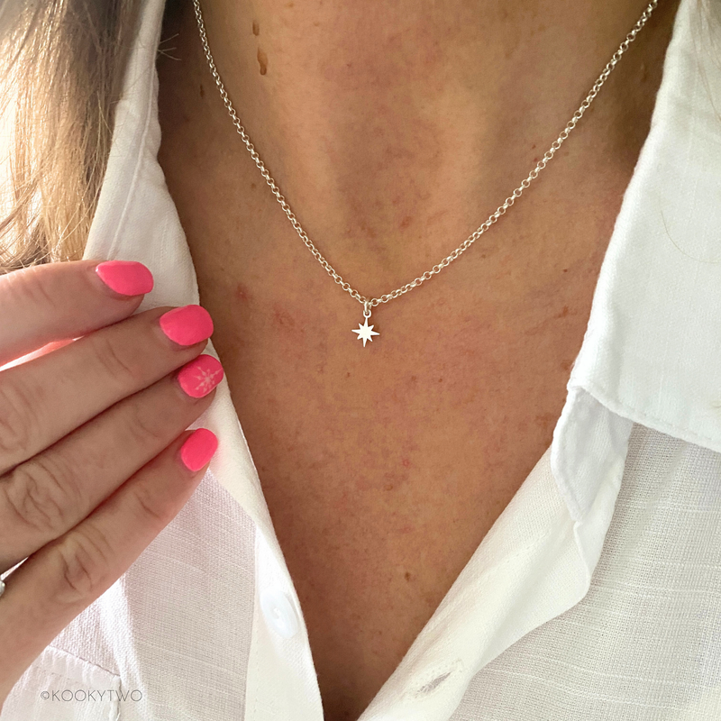 Close-up of a person wearing a delicate necklace with a pole star pendant in sterling silver.