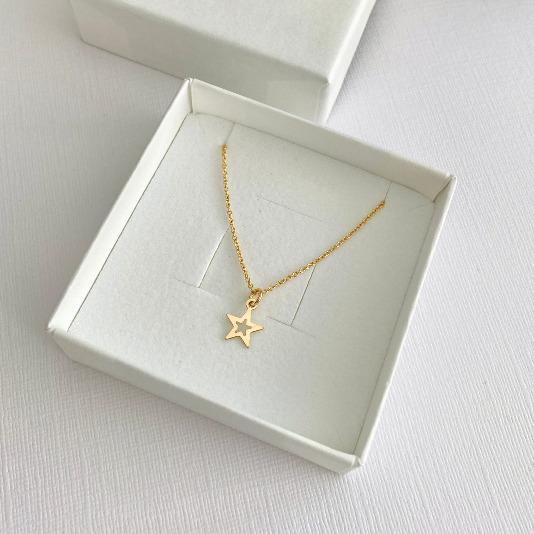 Gold star charm necklace in a white jewellery box