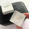 Rose quartz stone ring with adjustable band in a white box, held by a hand.