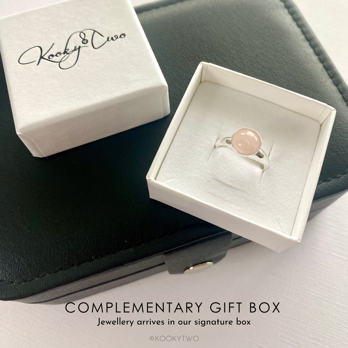 Rose quartz silver ring in a white box with KookyTwo branding. Rose quartz gemstone ring sits on a black jewellery box.