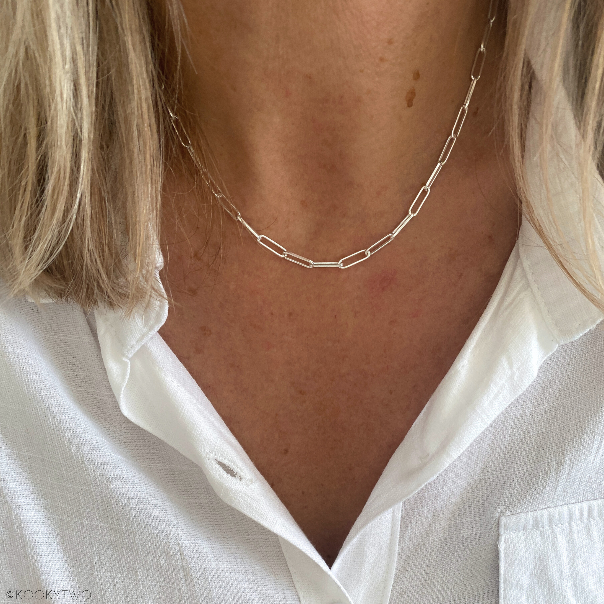 Close-up of a person wearing a Paperclip chain necklace in sterling silver with a white shirt.