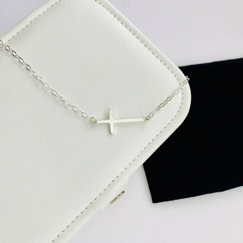 Silver cross necklace with cross pendant sitting horizontally on chain. KookyTwo.