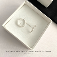 Mini hoop silver earrings with hinge opening in a white jewellery box.