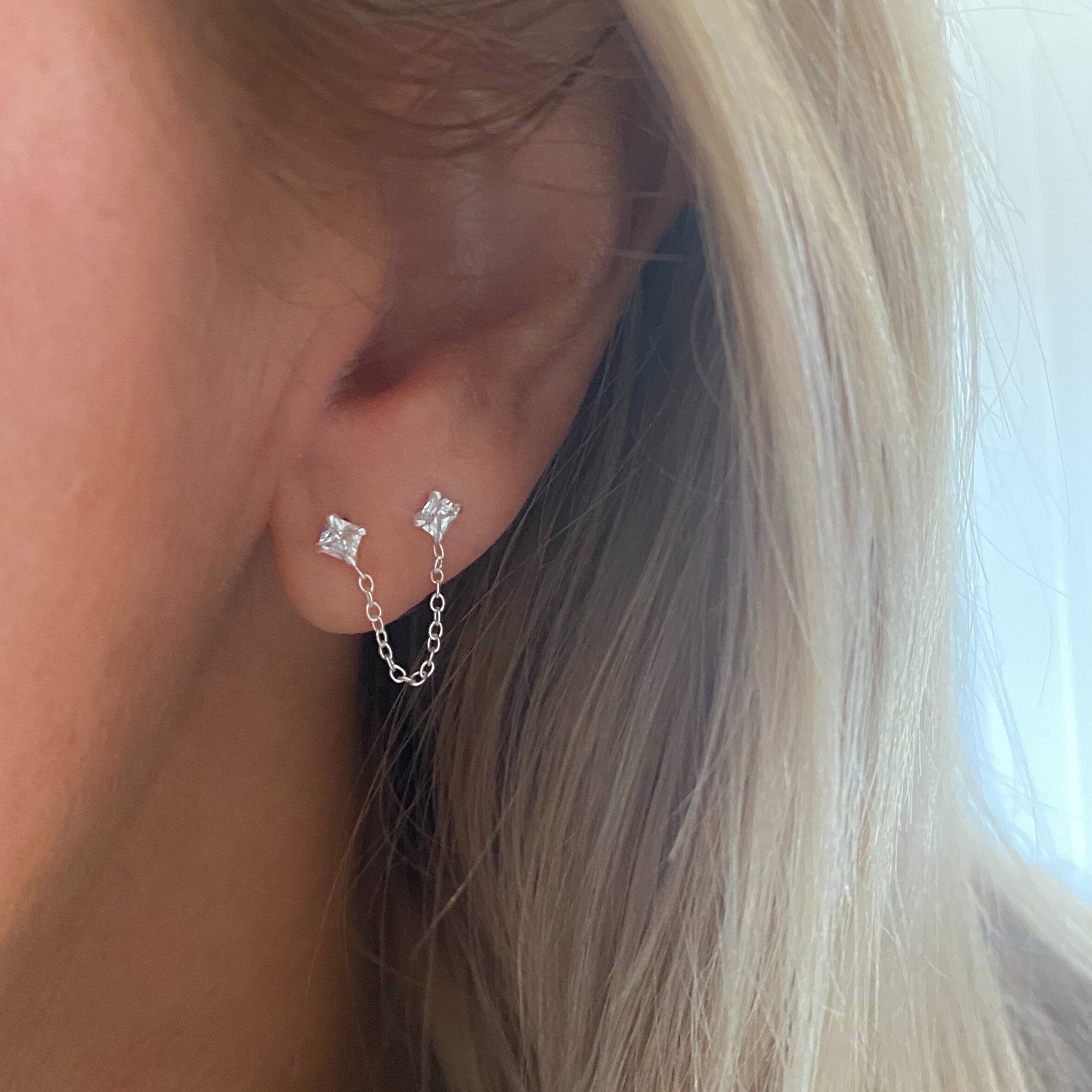 Lady wearing sterling silver and crystal ear jacket with chain between two crystal stones. 