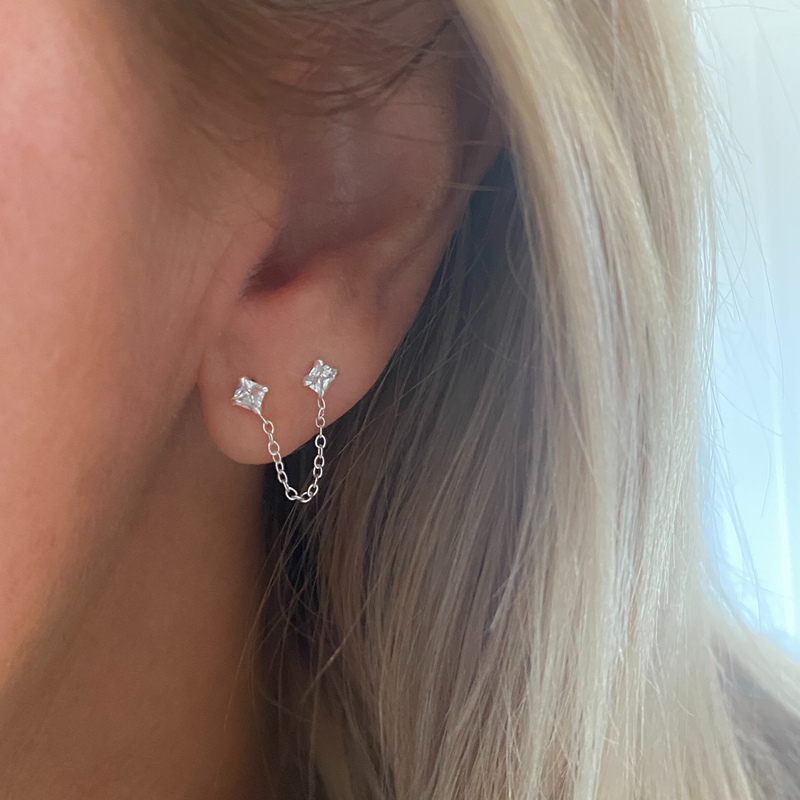 Lady wearing sterling silver and crystal ear jacket with chain between two crystal stones. 