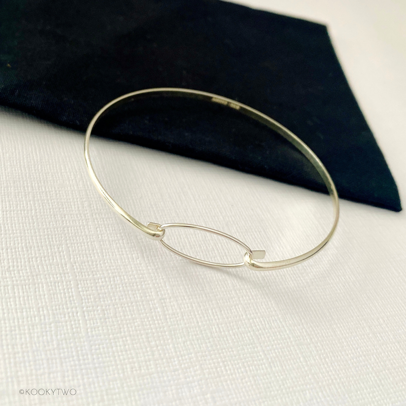 Sterling silver eternity bracelet with an oval charm on a slim bangle.