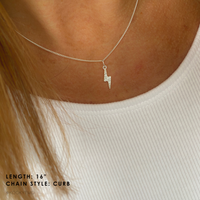 Sterling silver necklace with a lightning bolt pendant worn by a person, in a white top.