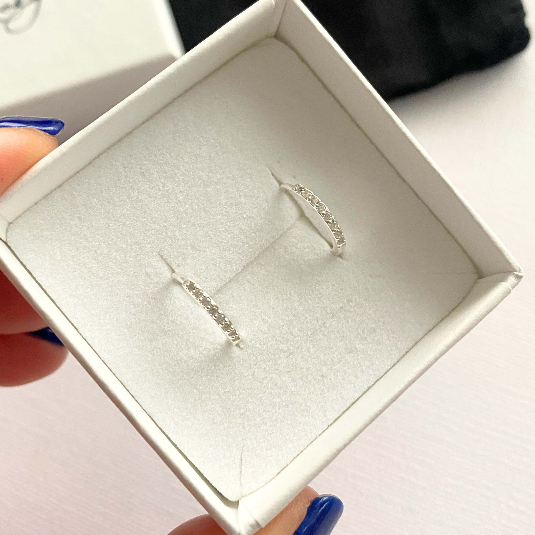 Silver earrings with crystal stones in a white jewellery box.
