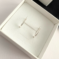 Silver crystal huggie earrings in a white jewellery box.