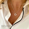 Star-shaped pendant necklace on a person wearing a white shirt.