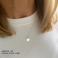 Silver pendant necklace worn by a person with a neutral top.