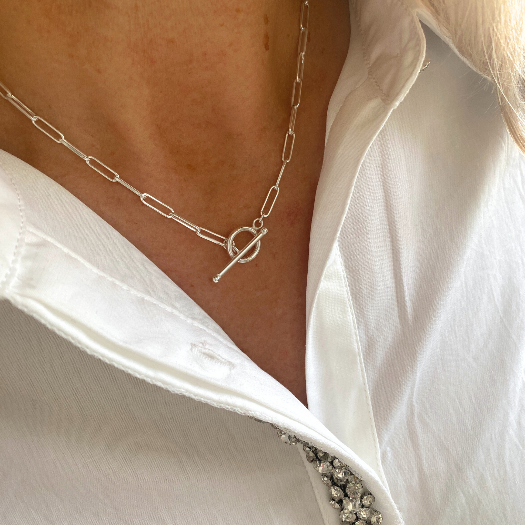 Sterling Silver long links chain necklace with a T Bar worn by a person in a white shirt.