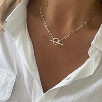 Silver t bar necklace with a paperclip chain, featuring long rectangular shaped links with a toggle fastening.
