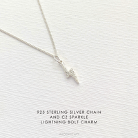 Sterling silver necklace with sparkle lightning bolt charm on a textured white background.