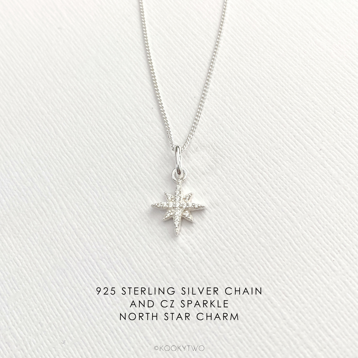 Silver sparkle star necklace with a north star charm on a white fabric background.