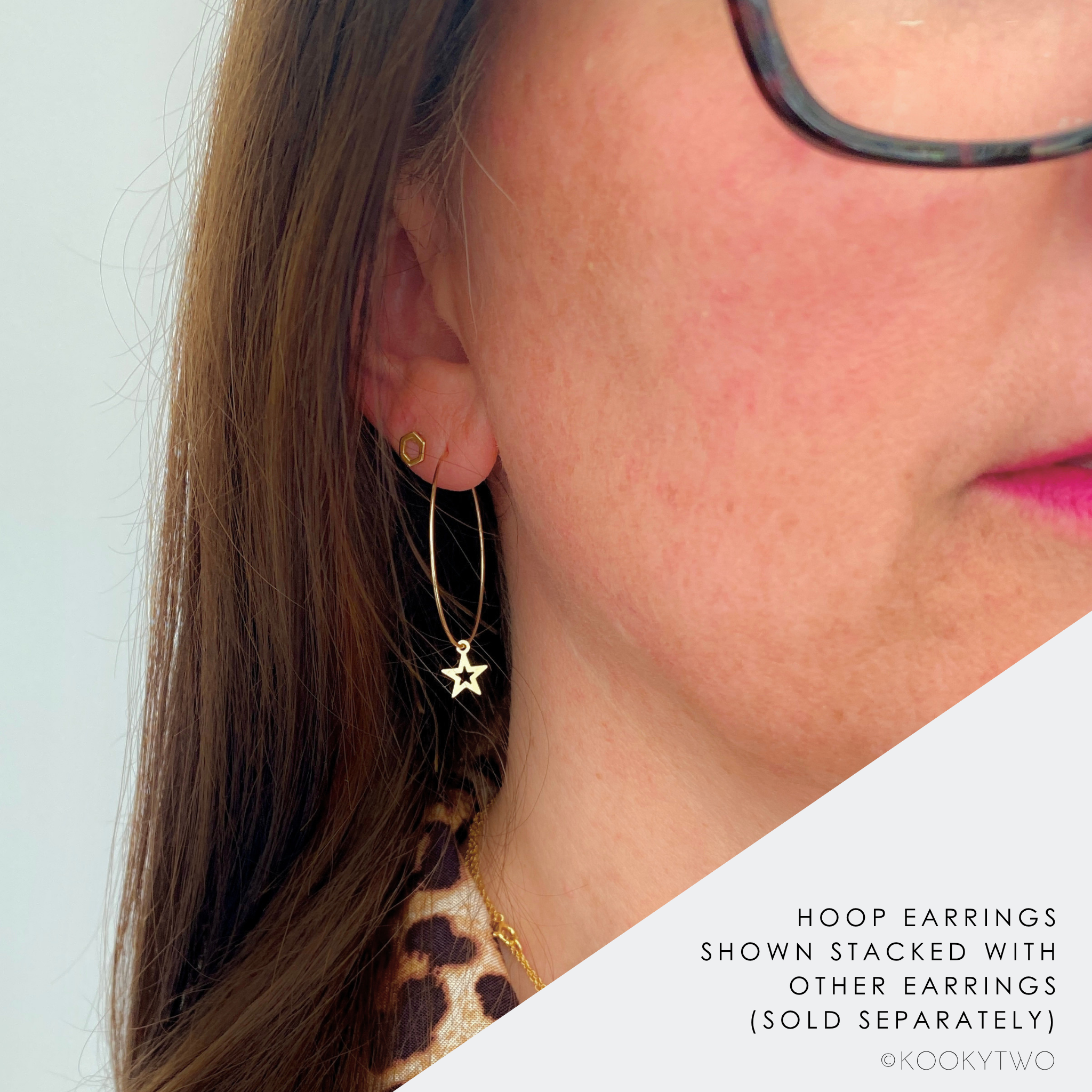Close of lady wearing a 14k gold filled hoop earring with a dangling star charm, shown stacked with other earrings.