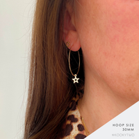 Close-up of a person's ear wearing a 30mm hoop earring in 14k gold filled with an open star charm hanging down. The image includes text in the bottom right corner reading 'HOOP SIZE 30MM' and 'KOOKYTWO'.